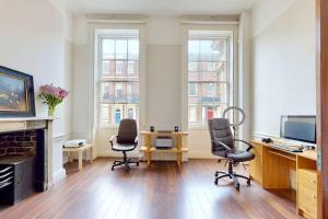 a living room with chairs and a desk and a fireplace at City Central Georgian House with Parking in Liverpool