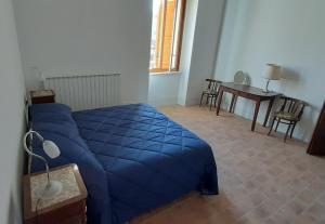 a bedroom with a blue bed and a table at Locanda di Posta in Camarda