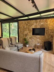 a living room with a couch and a stone wall at CHALÉ NAMATA 201 in São Roque