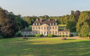 ein großes Haus auf einem grasbewachsenen Feld mit Bäumen in der Unterkunft Holiday Home Château de Boucéel Mont Saint Michel in Vergoncey