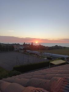 a sunset over a parking lot with the sun setting at Hotel Restaurante el Fornon in Novellana