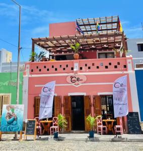 ein rosafarbenes Gebäude mit Stühlen und Tischen davor in der Unterkunft Luxury Beachhouse Apartment Boa Vista in Sal Rei
