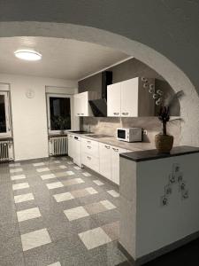 a kitchen with white cabinets and a checkered floor at Anka´s Ferienhaus in Bexbach