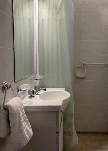 uma casa de banho com um lavatório, um espelho e um chuveiro em Hotel Rossetti y Spa em Mina Clavero