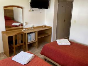 Habitación con 2 camas y escritorio con espejo. en Hotel Rossetti y Spa en Mina Clavero