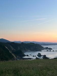 a view of the ocean at sunset from a hill at Hotel Restaurante el Fornon in Novellana