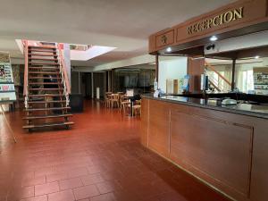 un restaurante con bar y una cocina con mesas en Hotel Rossetti y Spa en Mina Clavero