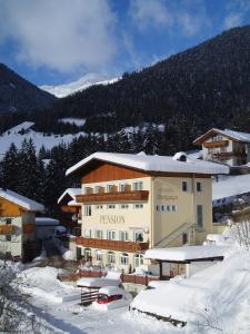 un gran edificio en la nieve con una montaña en Pension Bichlgeiger, en Anras