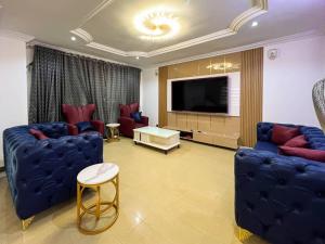 a living room with two blue couches and a television at Fey Pad in Lagos