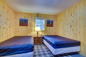 two beds in a room with wood paneled walls at Pet-Friendly Cabin Retreat Wisconsin River Access in Lyndon Station