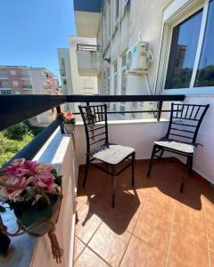 2 sillas y un jarrón de flores en un balcón en Holiday apartment, en Durrës