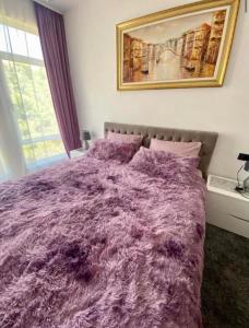 Un dormitorio con una cama morada con una foto en la pared en Holiday apartment, en Durrës