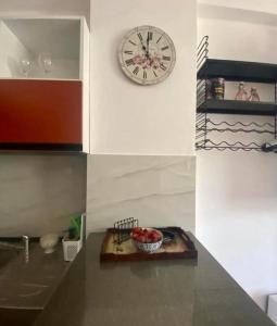 un reloj en una pared sobre un mostrador con un bol de fruta en Holiday apartment, en Durrës