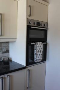 een keuken met witte kasten en een zwarte oven bij Remarkable 2-Bed House in Walesby Nottinghamshire in Elkesley