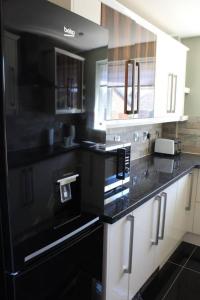 a kitchen with black counter tops and white cabinets at Remarkable 2-Bed House in Walesby Nottinghamshire in Elkesley