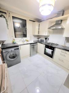 a kitchen with white cabinets and a dishwasher at Rooms close to QMUL in London