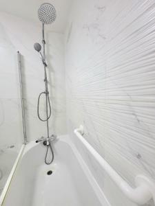 a white bathroom with a shower and a tub at Rooms close to QMUL in London