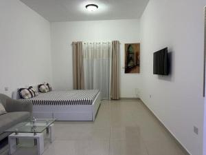 a white living room with a bed and a couch at Home away from Home in Ras al Khaimah