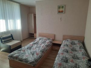Un dormitorio pequeño con dos camas y una silla. en Къща за гости Люляк, en Lyulyakovo