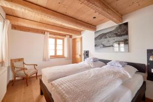 a bedroom with a large bed and a chair at Ferienhaus Steinbacher direkt am Tegernsee in Tegernsee