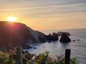 a sunset over the ocean with rocks in the water at Hotel Restaurante el Fornon in Novellana