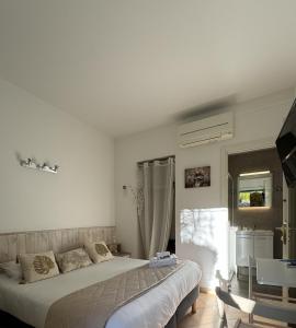 a white bedroom with a bed and a window at Hotel Pavillon Imperial in Menton