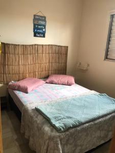 a bedroom with a bed with pink and blue sheets at Doce Refugio Itanhaém in Itanhaém