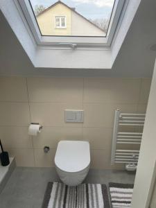 een badkamer met een wit toilet en een dakraam bij Boarding Suite in Wendlingen am Neckar