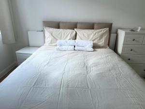 a white bed with two towels on top of it at 2 Bed Apartment in West Hampstead in London
