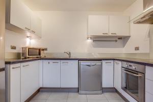 a kitchen with white cabinets and a microwave at 2 Bed Apartment in West Hampstead in London