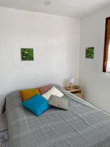 ein Bett mit bunten Kissen darauf im Schlafzimmer in der Unterkunft KARIFUNA in Le Souffleur