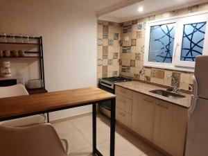 a kitchen with a table and a sink and a window at La Fragua Suites Líbano in El Bolsón