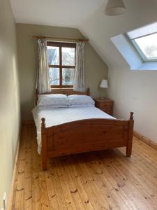 1 dormitorio con cama de madera y ventana en Letterfrack Farm Cottage in village on a farm beside Connemara National Park, en Letterfrack