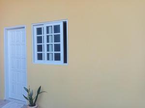 Casa blanca con ventana y maceta en Kitnet Mobiliada en Camaçari