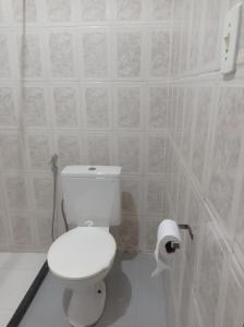 een witte badkamer met een toilet en een rol toiletpapier bij Kitnet Mobiliada in Camaçari