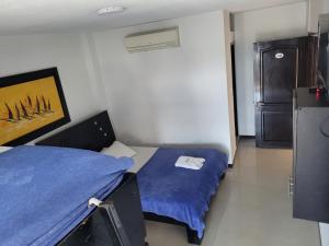 a small room with a bed and a refrigerator at Hotel Palmeras De Mariana in Bucaramanga