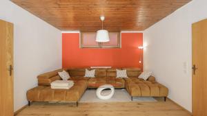 sala de estar con sofá marrón y paredes de color naranja en Appartement auf dem Schlossberg, en Fieberbrunn