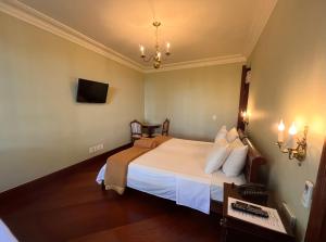 a bedroom with a bed and a desk and a television at Aroso Paço Hotel in Pedra Azul