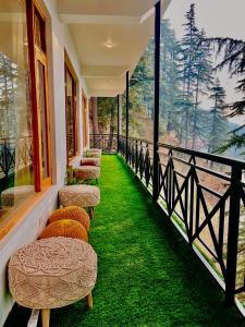 a row of chairs on a balcony with green grass at Unwind Stays in Nagar