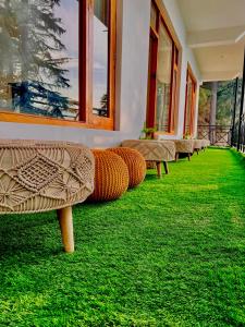 a row of benches sitting in a room with green grass at Unwind Stays in Nagar