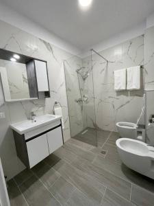a white bathroom with a sink and a toilet at Melody Apartment in Korçë in Korçë