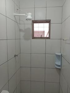 a white tiled bathroom with a window and a toilet at Tedesco in Palmas