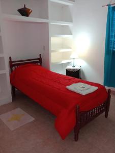 a bedroom with a red bed with a red blanket at M y M Departamento in Belén