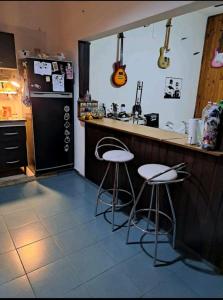 a kitchen with two stools at a counter and a refrigerator at Pink house in Buenos Aires