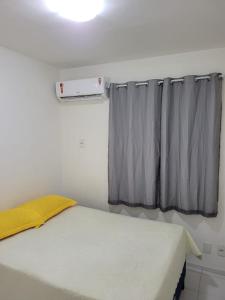 a bedroom with a bed and a window with a yellow pillow at SUA ESTADIA PERFEITA in São Luís