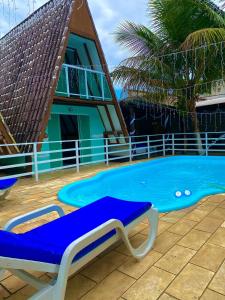 uma piscina azul com uma chaise longue ao lado de uma casa em Marcelo Chale em Paraty
