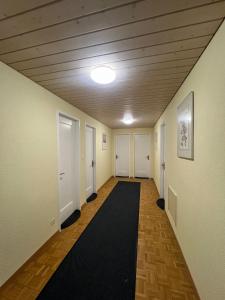 a hallway with white doors and a black rug at Niederdorf, Baselland Hotel in Niederdorf