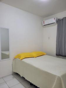 a white bedroom with a bed with a yellow blanket at SUA ESTADIA PERFEITA in São Luís