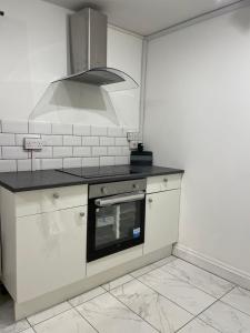 uma cozinha com armários brancos e um forno com placa de fogão em Double bedroom with bathroom en suite in London Docklands Canary Wharf E14 em Londres