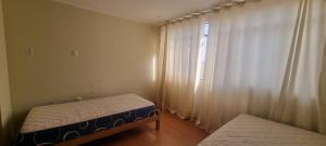 een slaapkamer met 2 bedden en een raam met gordijnen bij Casa / Departamento en Chiclayo in Chiclayo